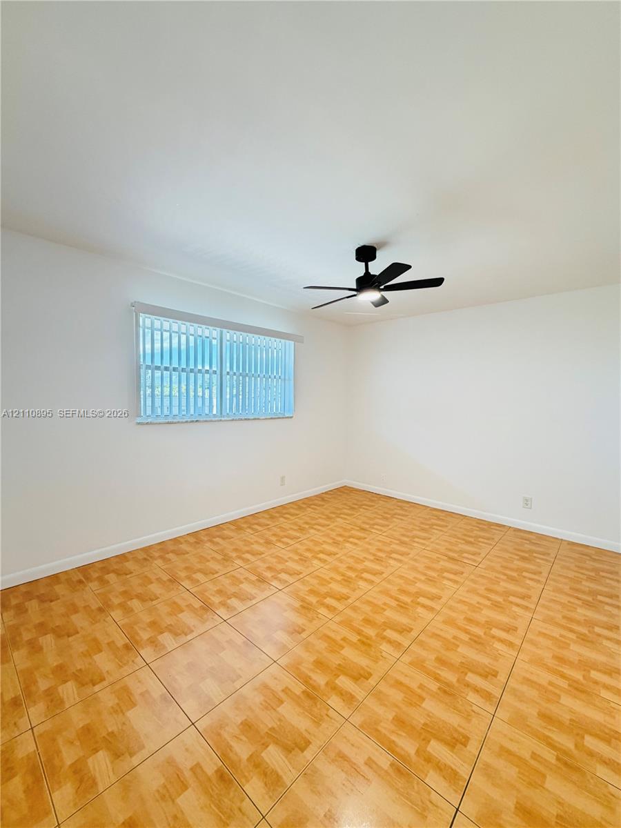 Neutral interior featuring tile flooring, a matte black ceiling fan, and a horizontal window with vertical blinds