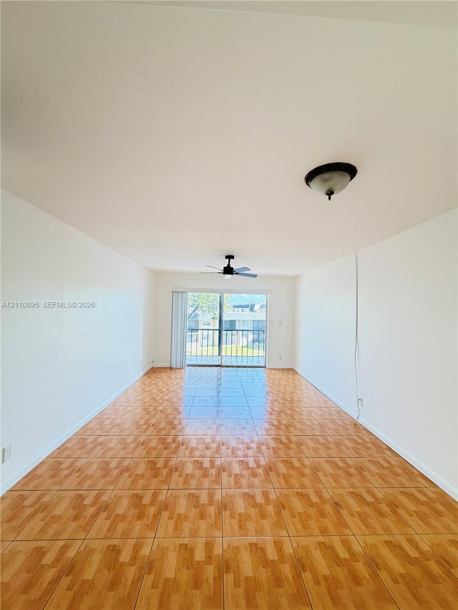 Interior space featuring tile flooring, ceiling fan with light fixture, flush-mount lighting, and sliding glass door with access to a balcony