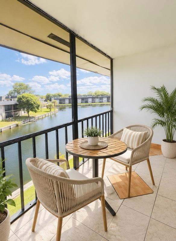 Screened-in balcony featuring tile flooring, metal railings, and direct water exposure