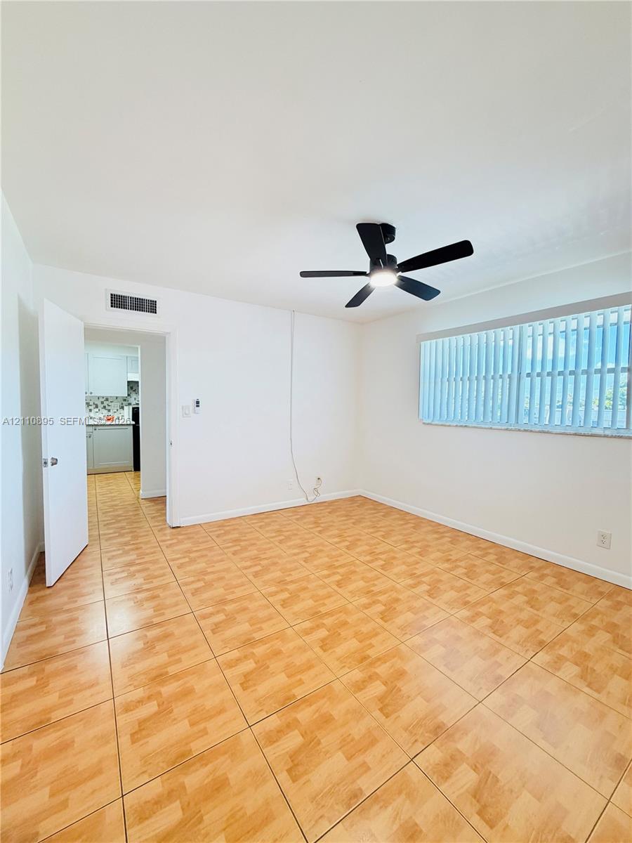 Room featuring wood-finish tile flooring, a multi-blade ceiling fan with integrated lighting, and vertical window blinds