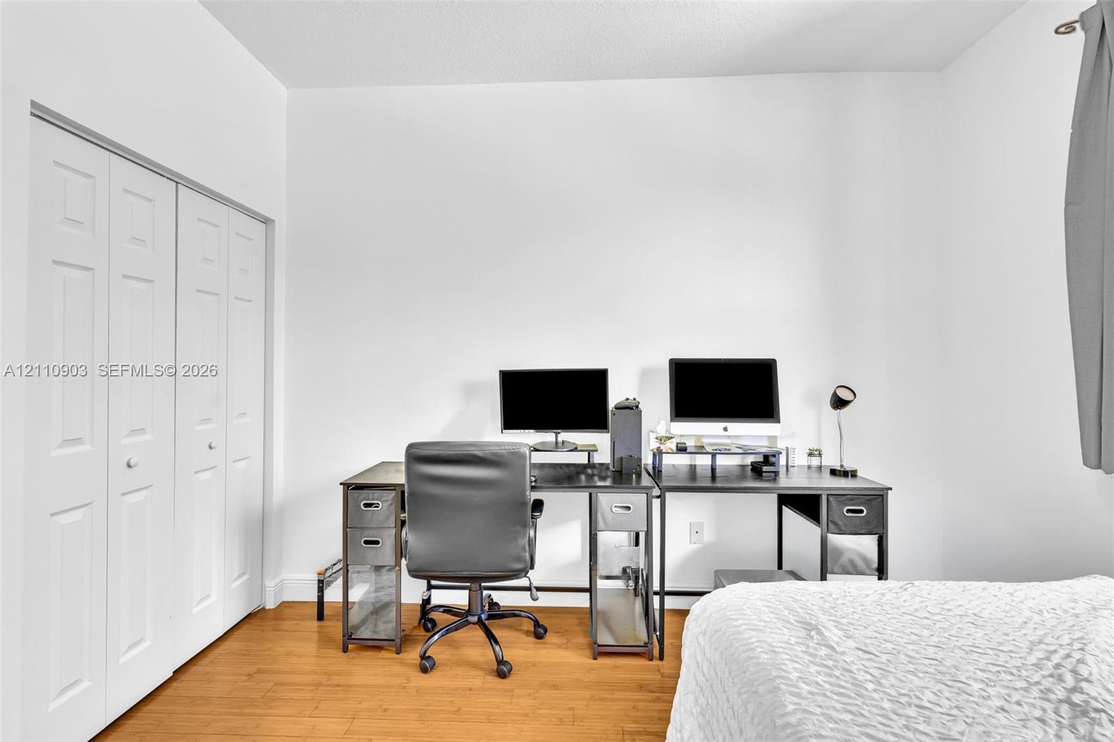 Room featuring wood-finish flooring, white walls, and a bi-fold closet with white panel doors