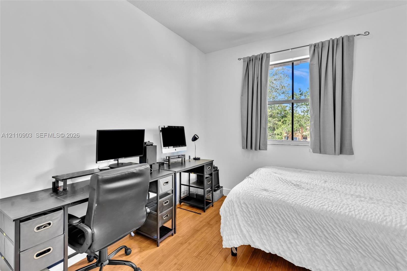Interior room featuring wood-finish flooring and a single window with a decorative curtain rod