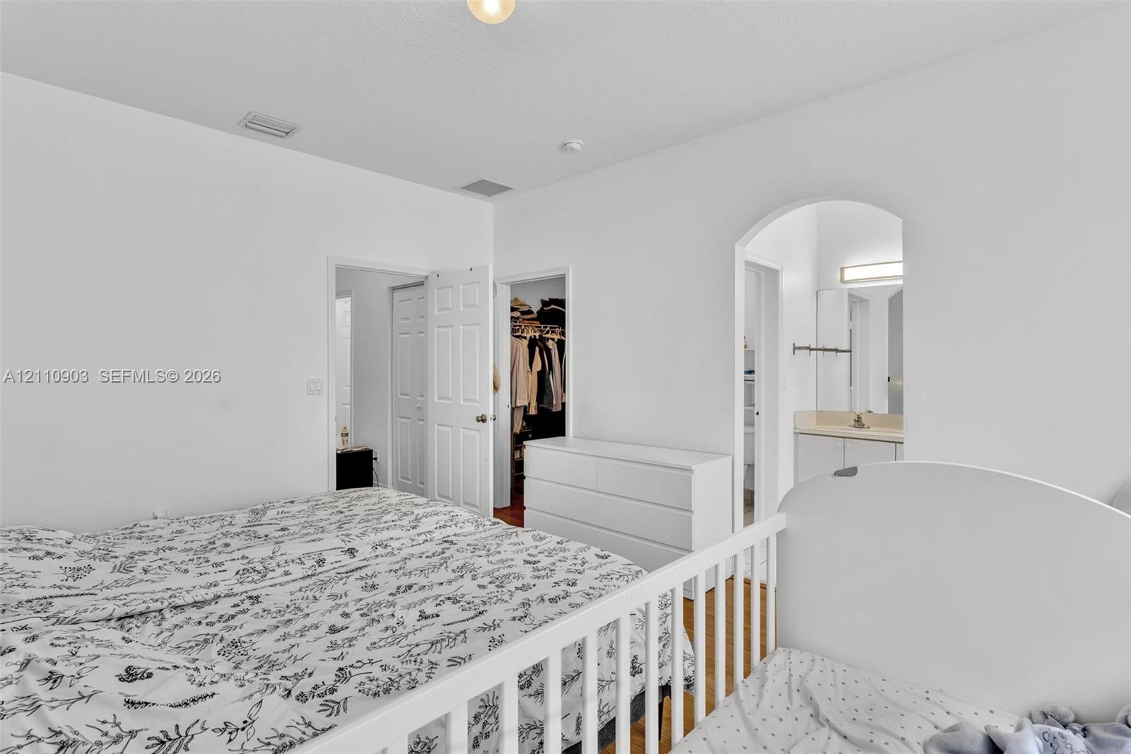 Neutral-toned interior space featuring high ceilings, a classic arched doorway, and white paneled interior doors