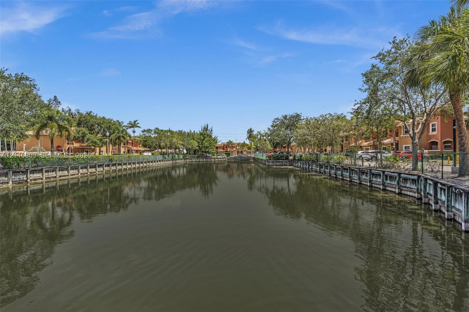 Waterfront setting featuring a concrete seawall, mature palm trees, and manicured perimeter landscaping