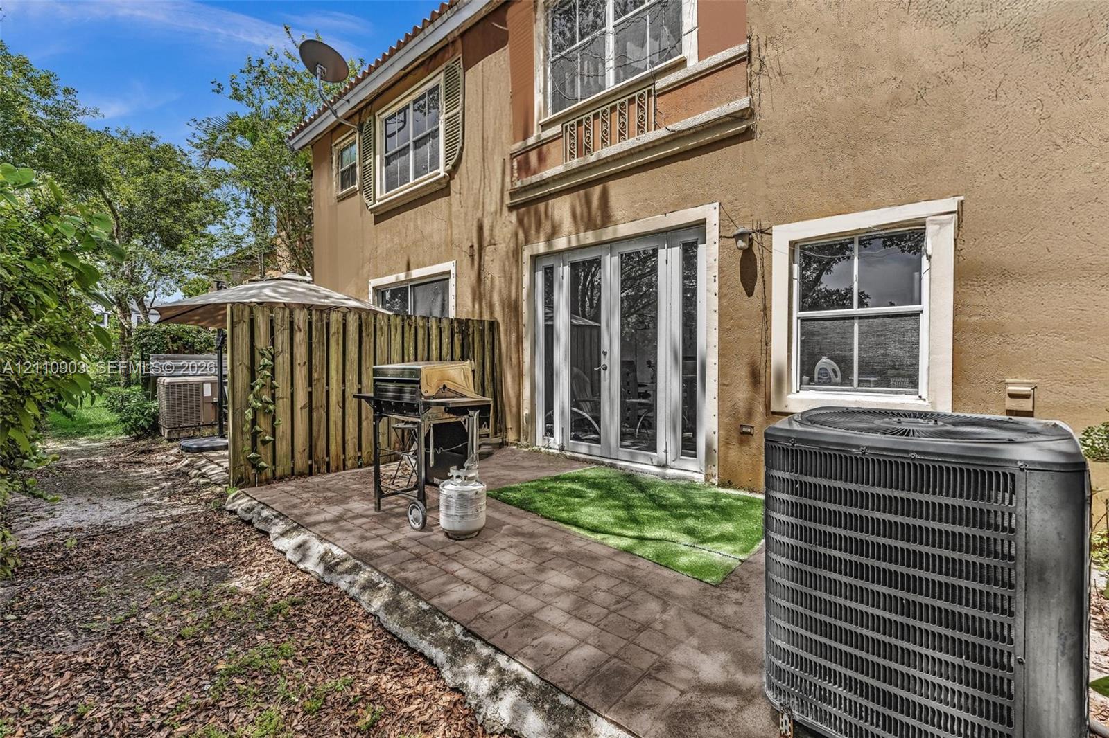 Stucco exterior featuring a paver patio, multi-pane windows, decorative shutters, and glass-paneled double doors