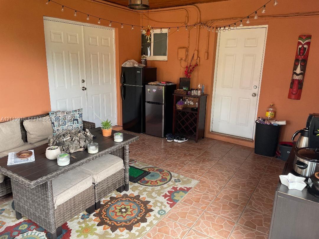 Covered patio featuring ceramic tile flooring, wood-paneled ceiling, and two sets of white-paneled entry doors