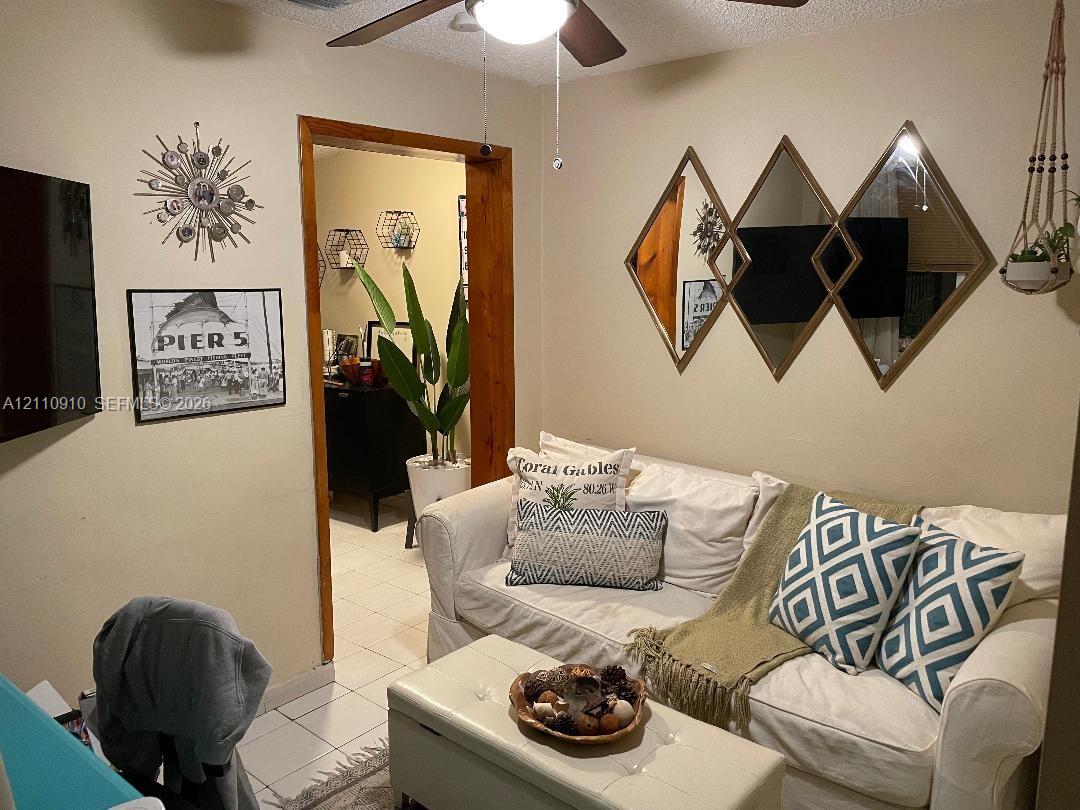 Interior space featuring ceramic tile flooring, a natural wood-trimmed doorway, and a ceiling fan with integrated lighting
