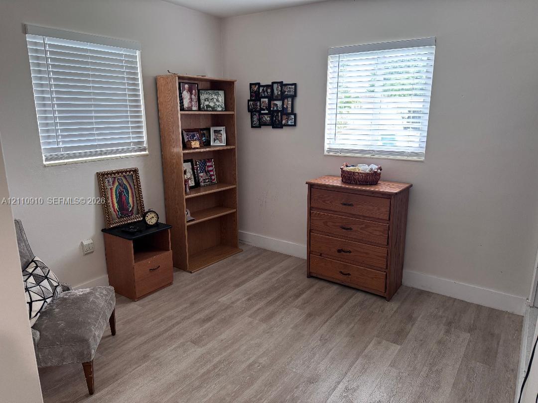 Room featuring neutral-toned walls, wood-finish flooring, and two windows equipped with horizontal blinds