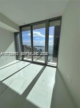 Floor-to-ceiling glass sliding doors, large-format tile flooring, and metal-framed windows featuring coastal scenery