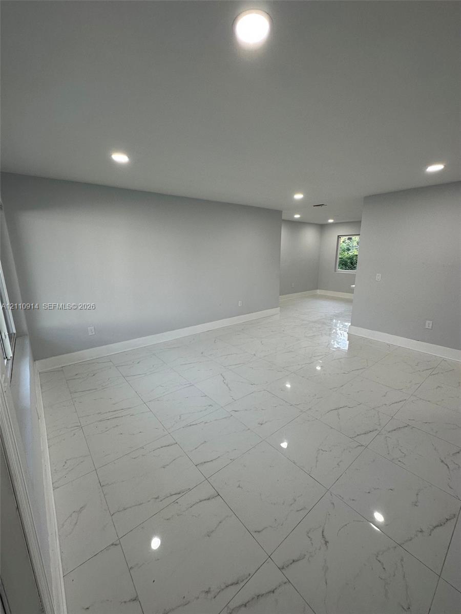 Interior space featuring light-toned neutral walls, large-format polished tile flooring with marble-style veining, and recessed ceiling lighting