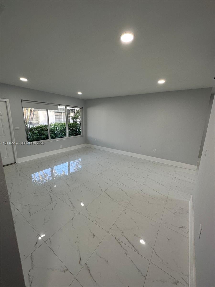 Neutral-toned interior featuring white tile flooring with grey veining, recessed ceiling lighting, and a large multi-pane window