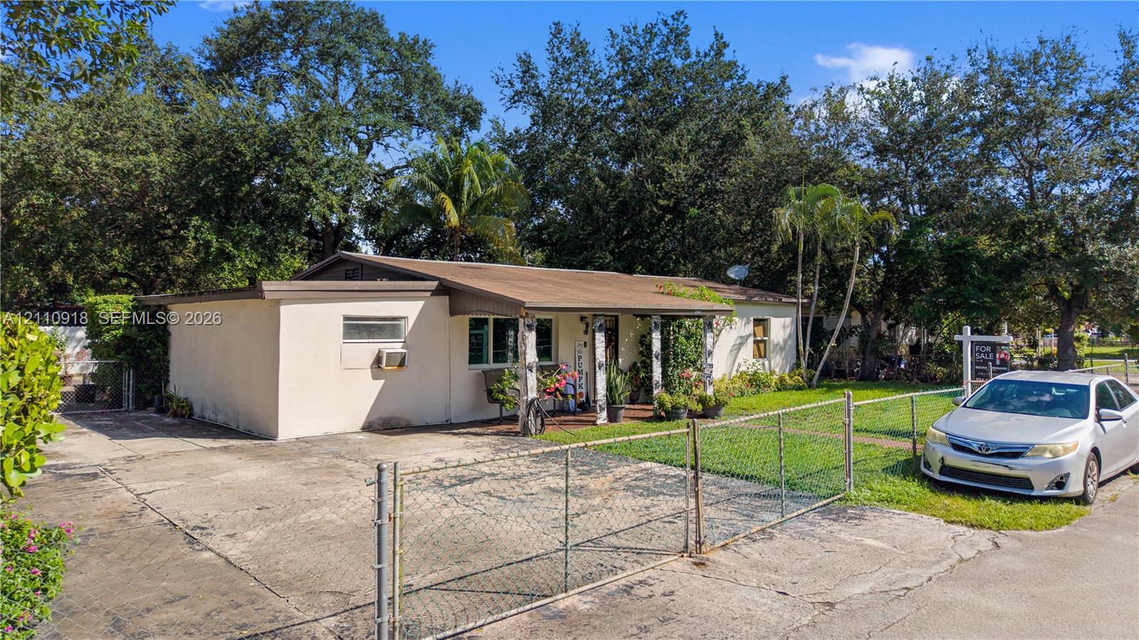Single-story exterior featuring a concrete driveway, metal chain-link fencing, and a covered entryway