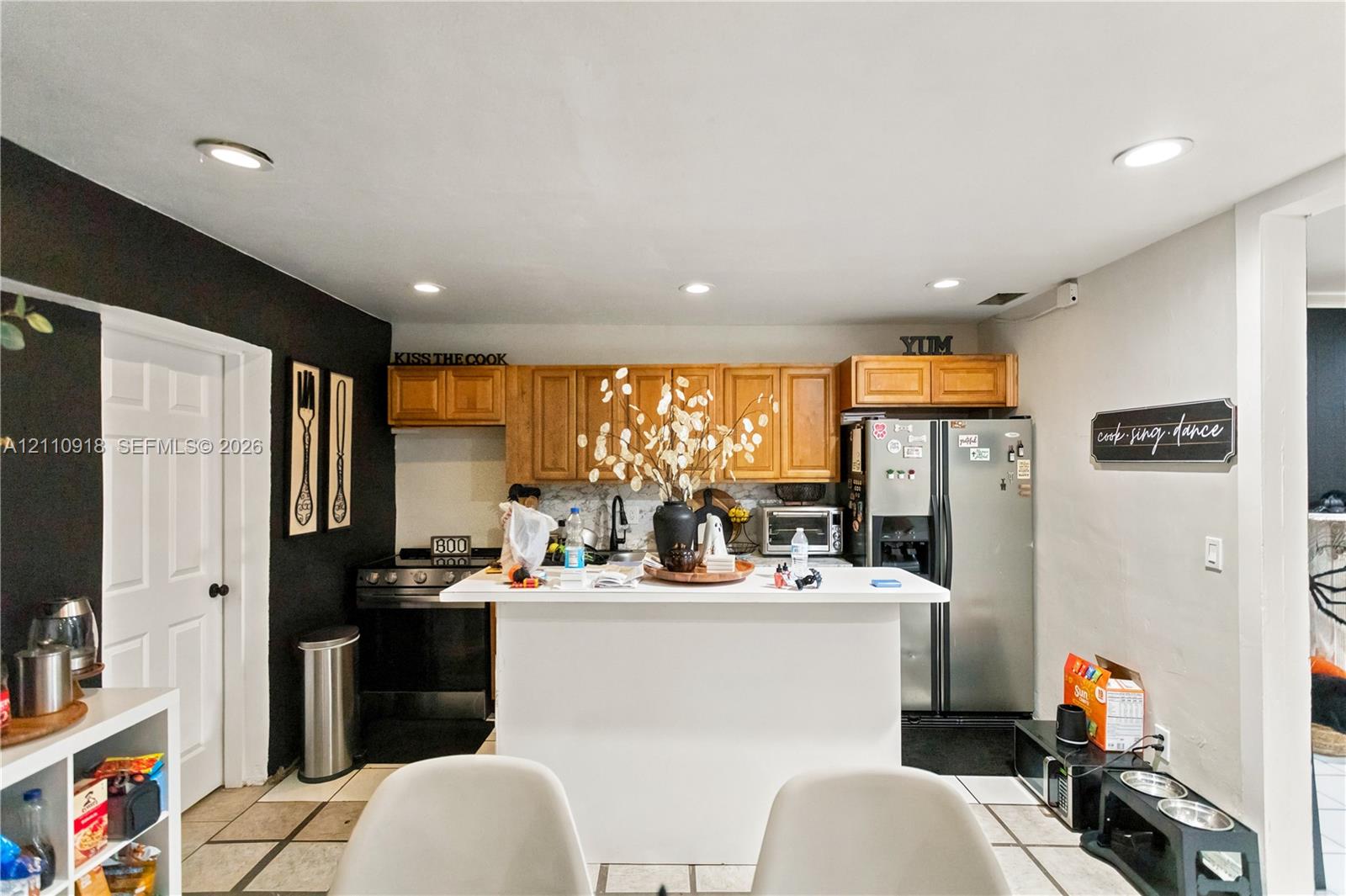 Kitchen featuring wood cabinetry, a central island with a white countertop, recessed lighting, and tile flooring