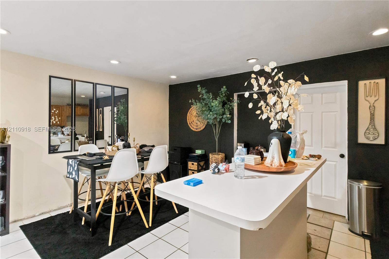Solid-surface countertop island, recessed ceiling lighting, wall-mounted multi-panel mirror, and tile flooring