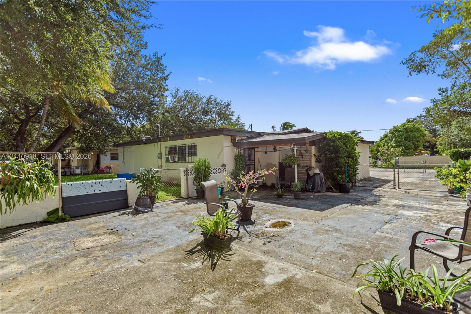 Exterior area featuring a concrete patio, a covered porch, perimeter fencing, and mature trees Exterior area featuring a concrete patio, a covered porch, perimeter fencing, and mature trees