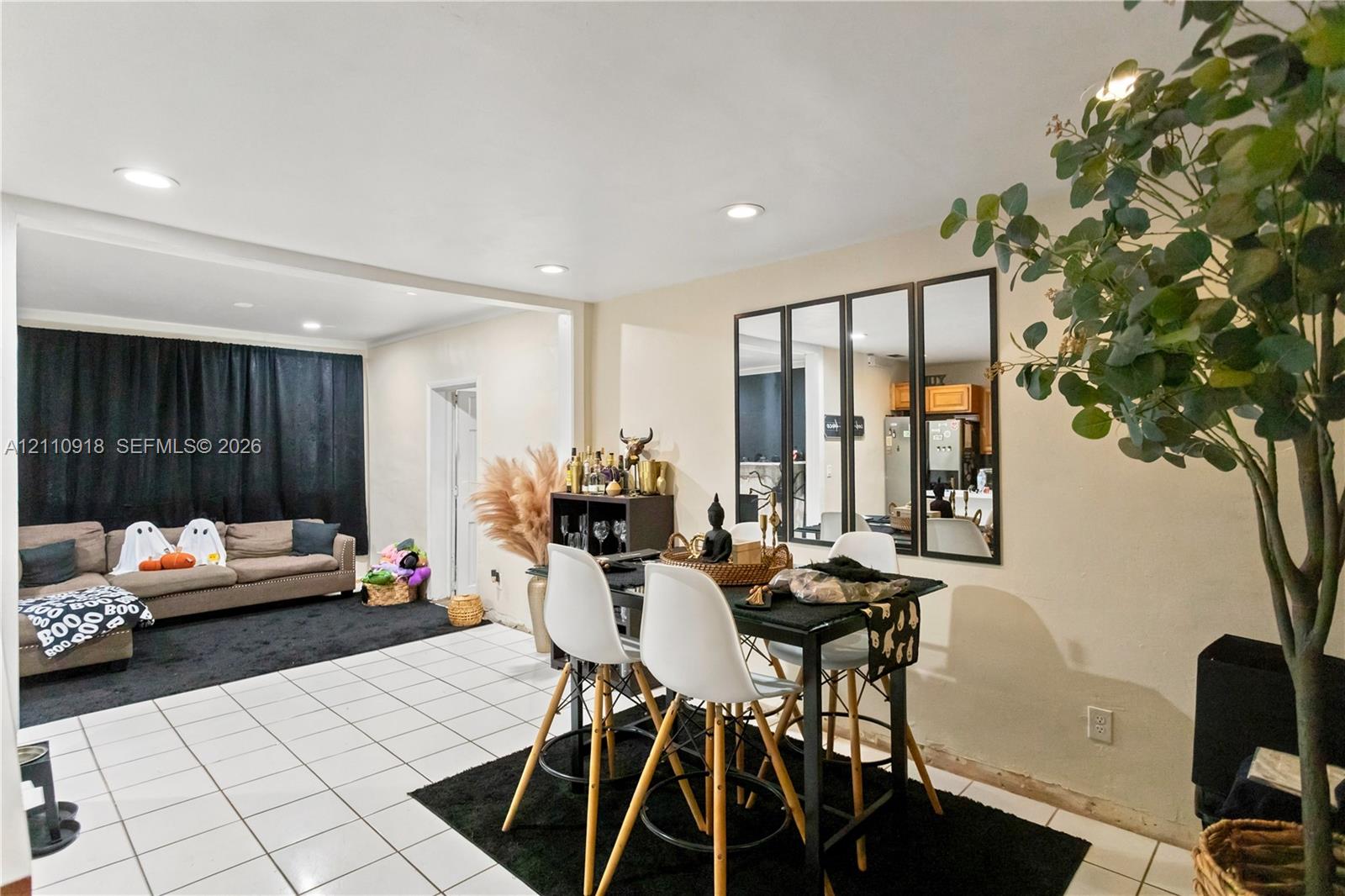 Open-concept interior featuring light-toned tile flooring, recessed ceiling lighting, and a multi-pane decorative wall mirror