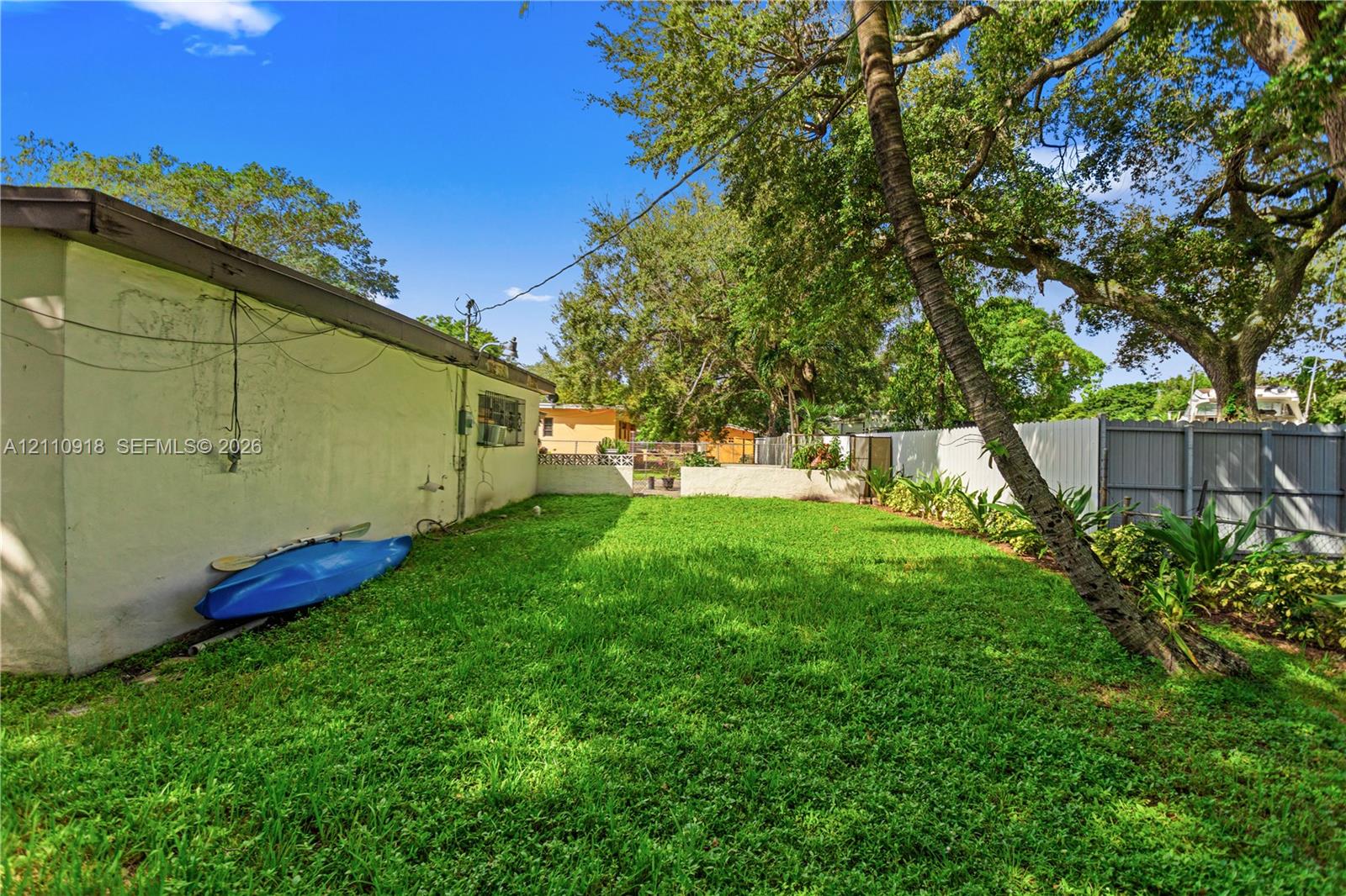 Side yard featuring a grass lawn, mature trees, and perimeter fencing