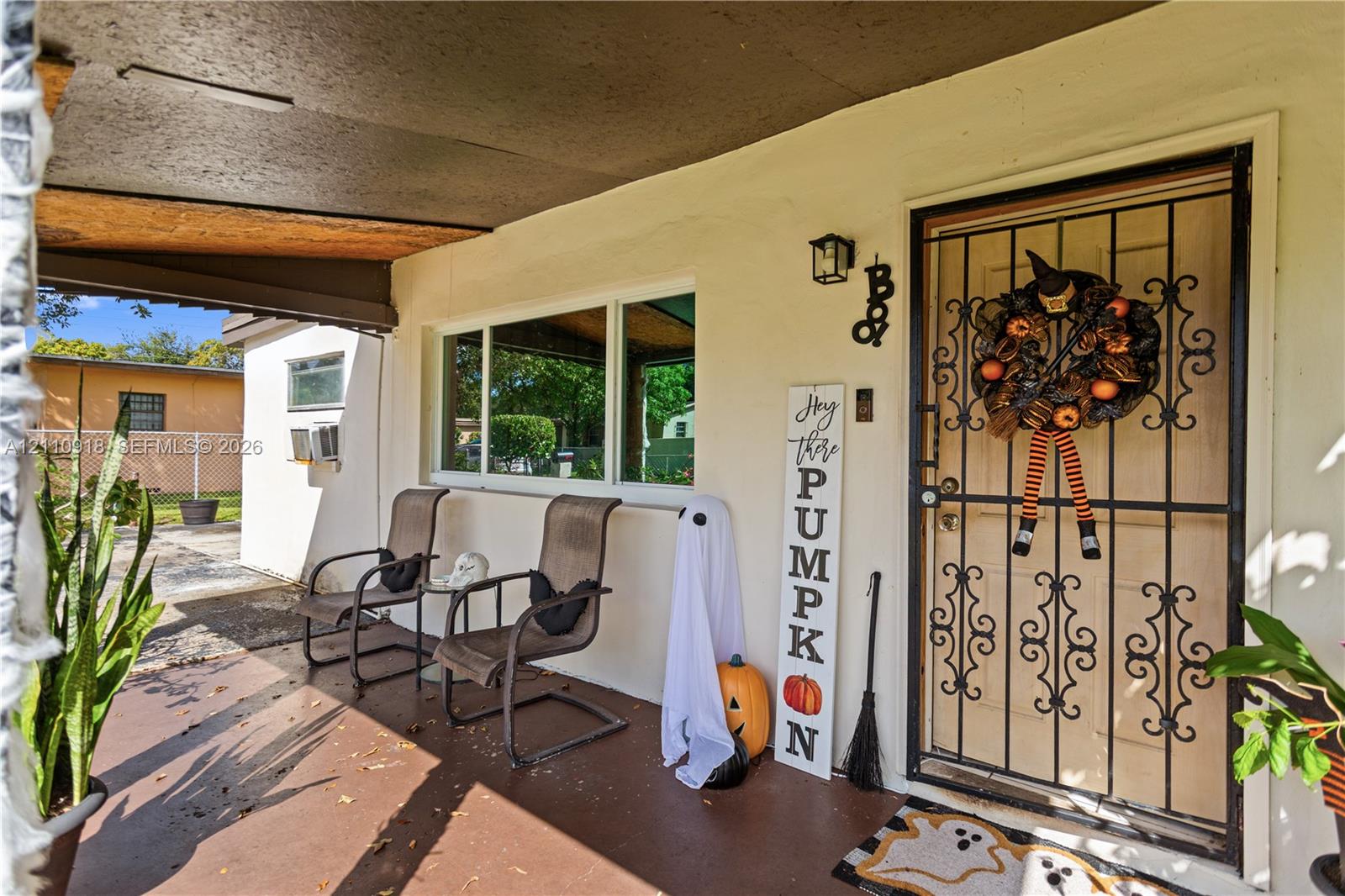 Covered front porch featuring a decorative wrought-iron security door, smooth stucco exterior finish, and wall-mounted exterior lighting Covered front porch featuring a decorative wrought-iron security door, smooth stucco exterior finish, and wall-mounted exterior lighting