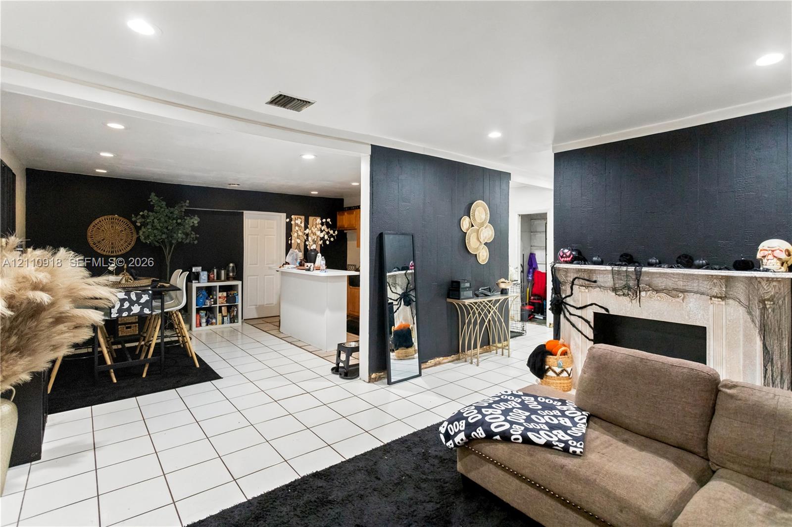 Open-concept interior featuring light-toned tile flooring, recessed ceiling lighting, and a fireplace with a stone-finish surround