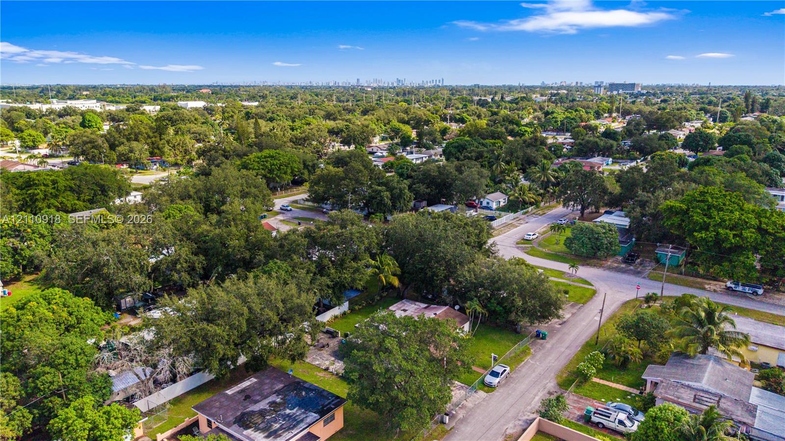 Aerial perspective of a residential lot featuring mature trees, perimeter fencing, and established vegetation