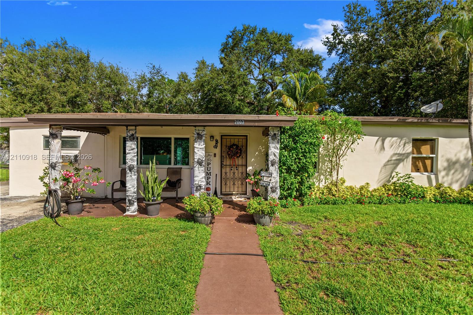 Single-story exterior featuring a concrete walkway, covered front porch, textured masonry support columns, and metal security door Single-story exterior featuring a concrete walkway, covered front porch, textured masonry support columns, and metal security door
