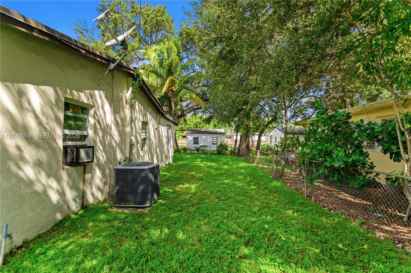 Side yard featuring a grass lawn, chain-link perimeter fencing, and mature trees Side yard featuring a grass lawn, chain-link perimeter fencing, and mature trees