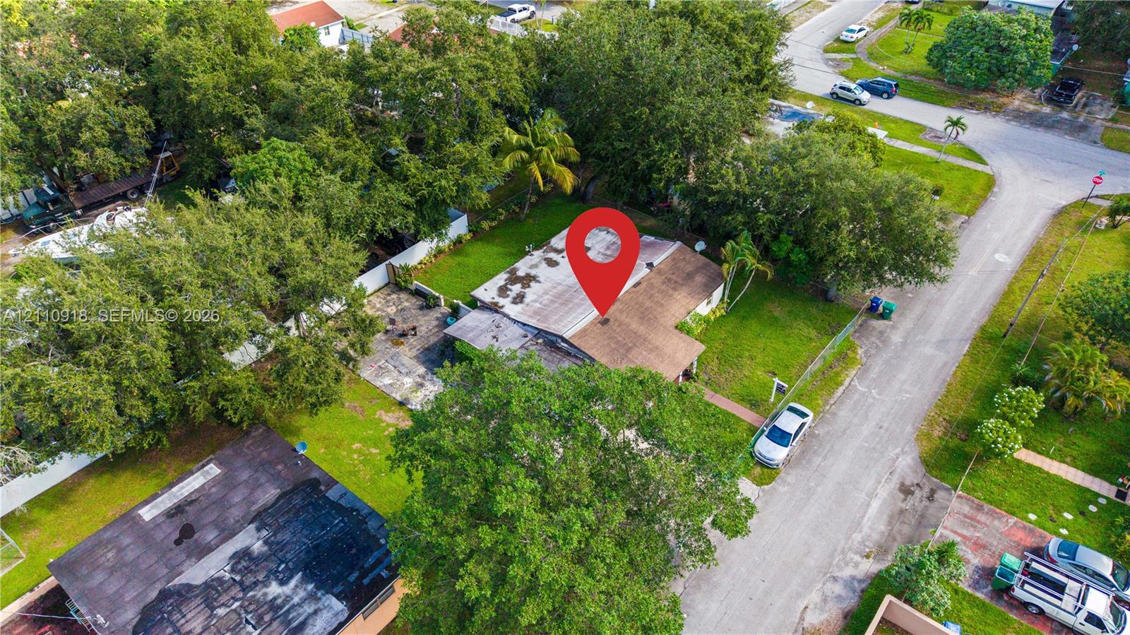 Aerial perspective featuring a shingled roof, paved driveway, expansive lawn, and mature trees