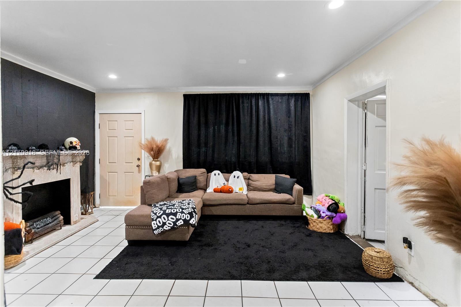 Living area featuring large-format tile flooring, recessed lighting, and a prominent fireplace with a decorative stone-finish mantel