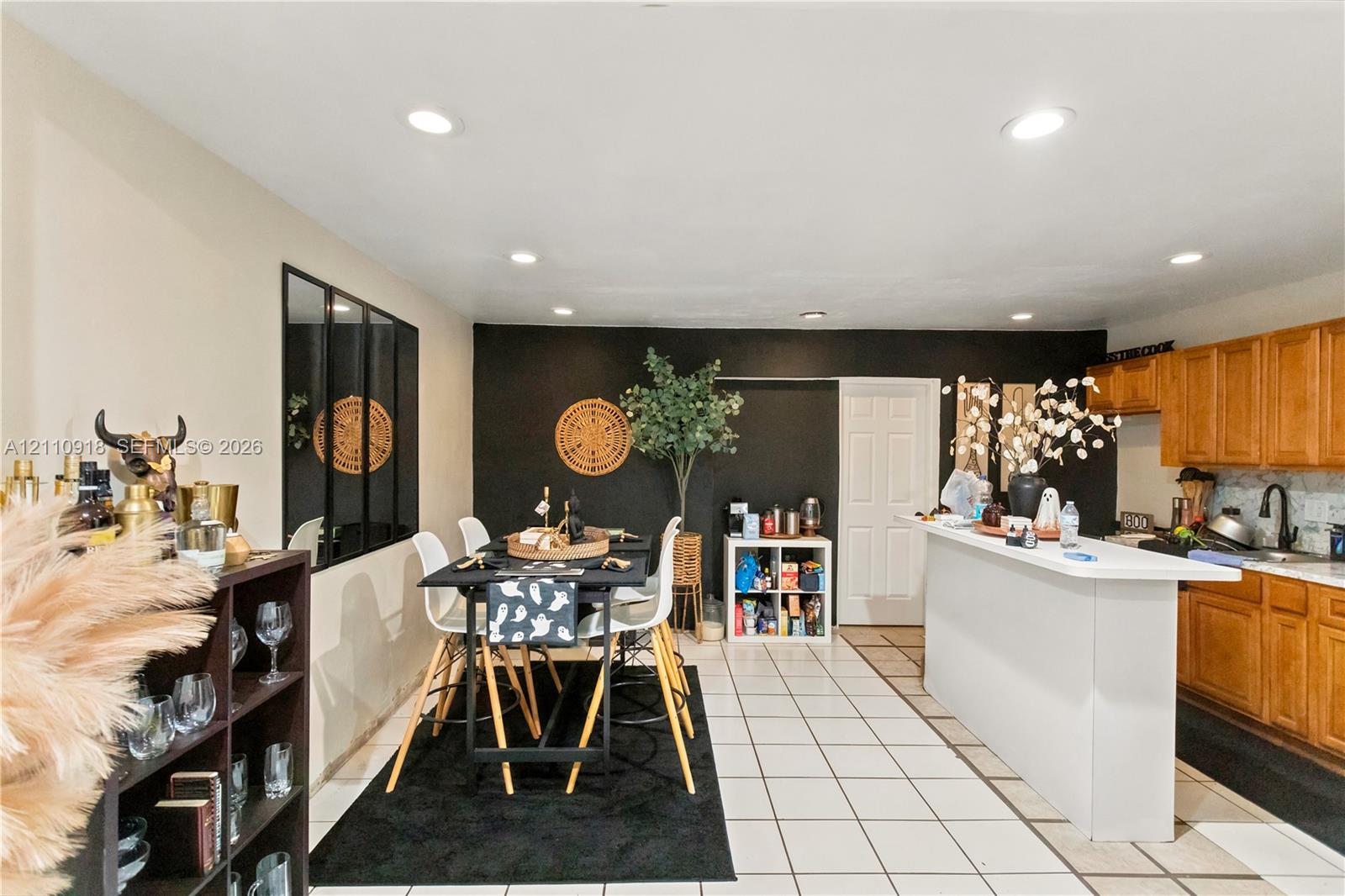 Kitchen featuring wood cabinetry, white countertops, a breakfast bar, recessed lighting, and tile flooring