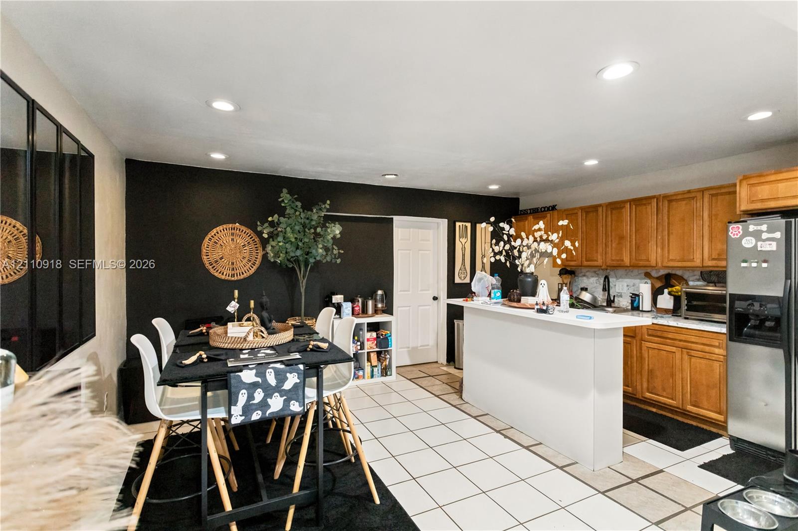 Kitchen featuring light wood cabinetry, white tile flooring, recessed ceiling lighting, and a peninsula island with a solid surface countertop