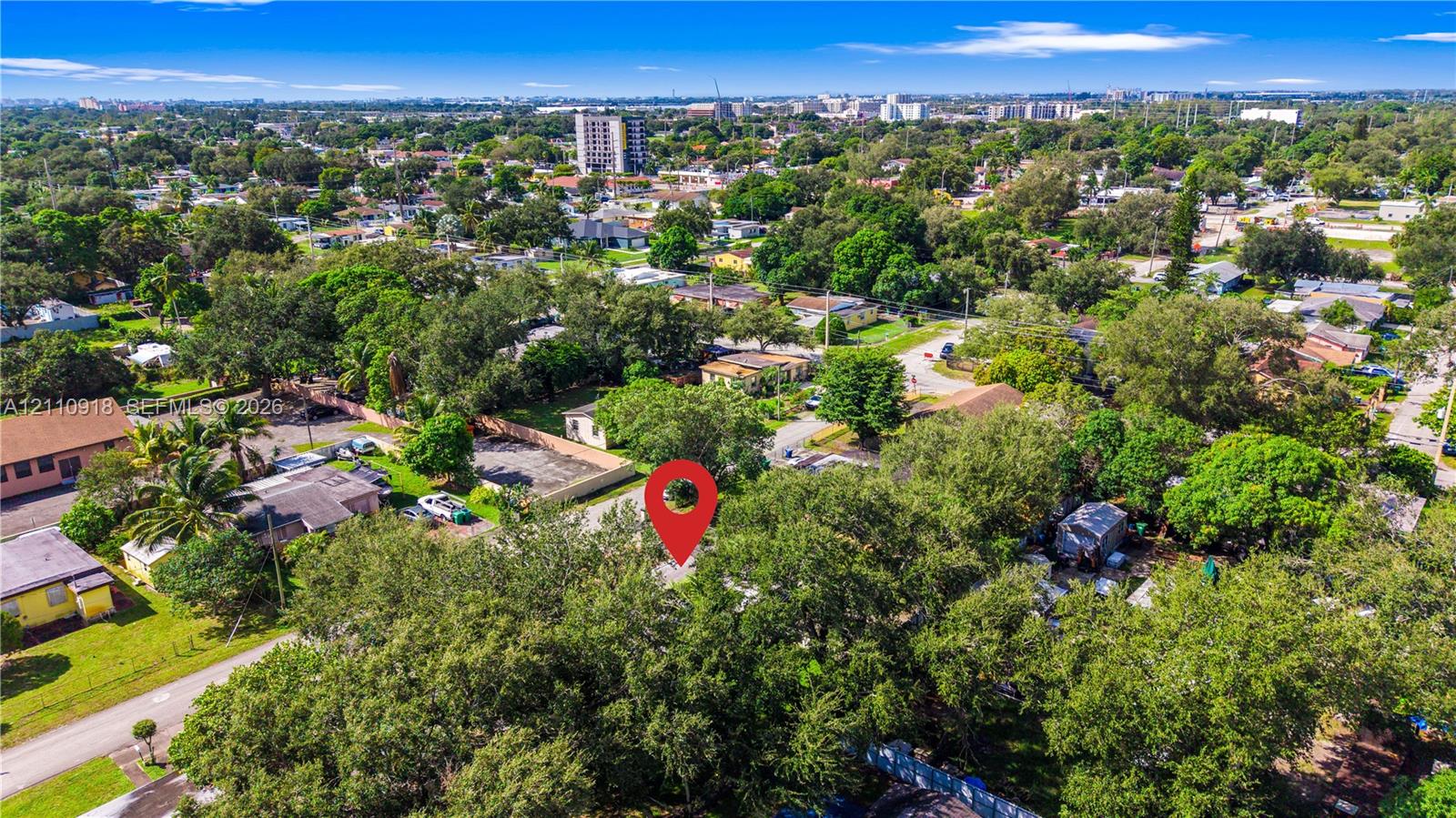 Aerial perspective featuring a residential lot characterized by mature tree canopy and paved street access within an established suburban setting