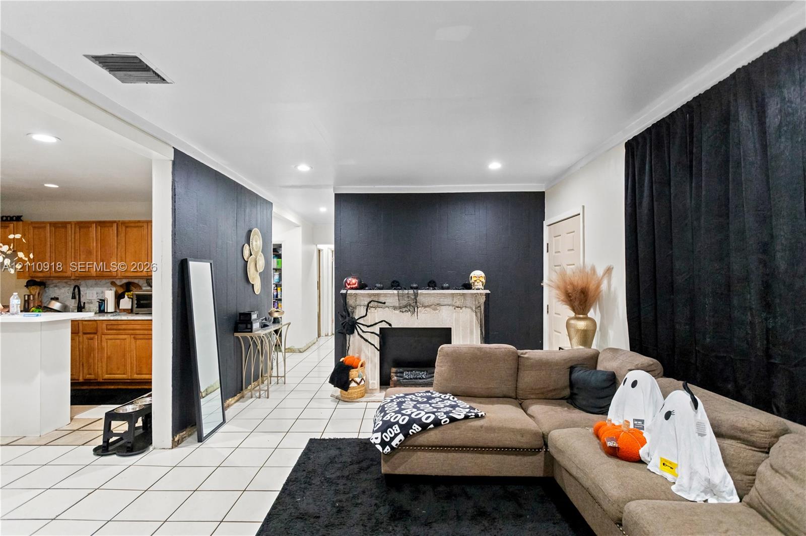 Open-concept interior featuring light-toned tile flooring, recessed lighting, and a prominent fireplace with a decorative mantel