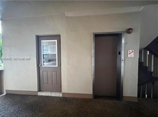 Single-panel entry door with window insert and elevator access featuring brushed metal framing