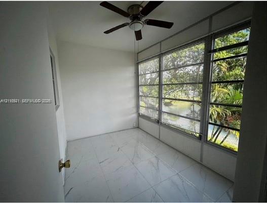 Sunroom featuring large-format tile flooring, multi-pane windows, and a ceiling fan with integrated lighting