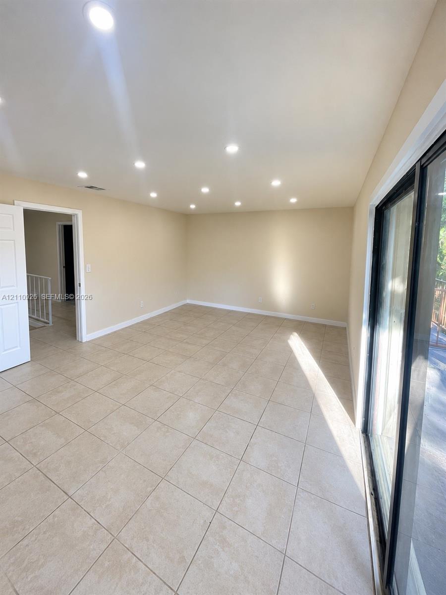 Interior space featuring large-format ceramic tile flooring, recessed ceiling lighting, and expansive glass sliding doors