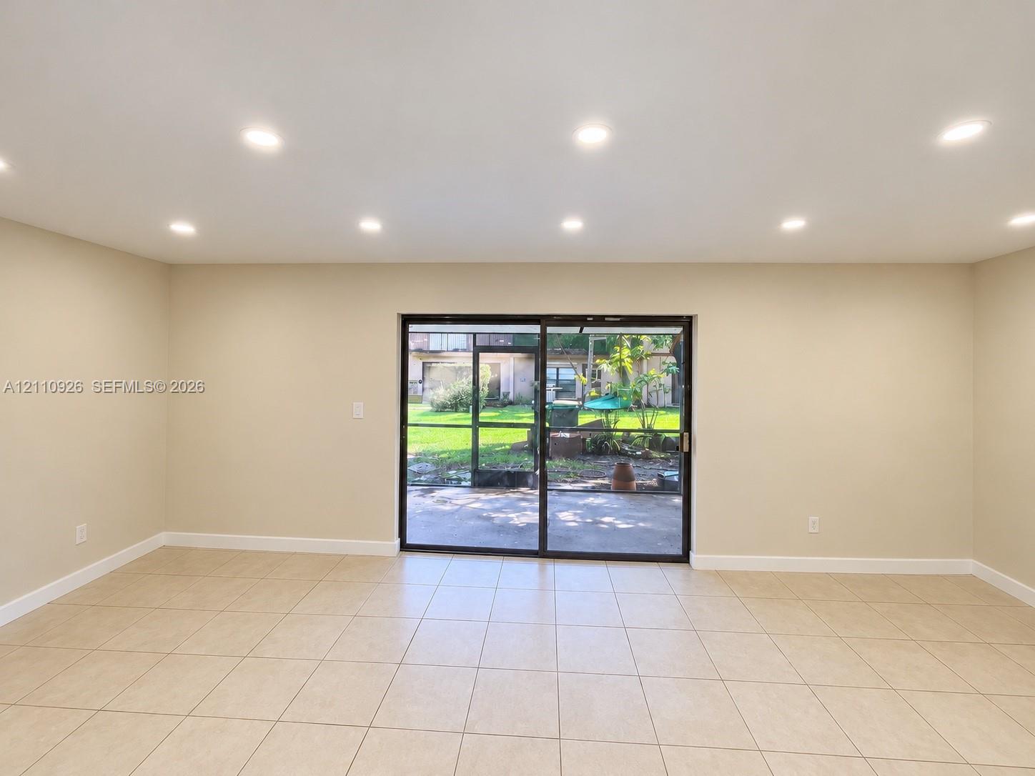 Spacious interior featuring large-format tile flooring, recessed lighting, and sliding glass doors opening to a screened-in lanai