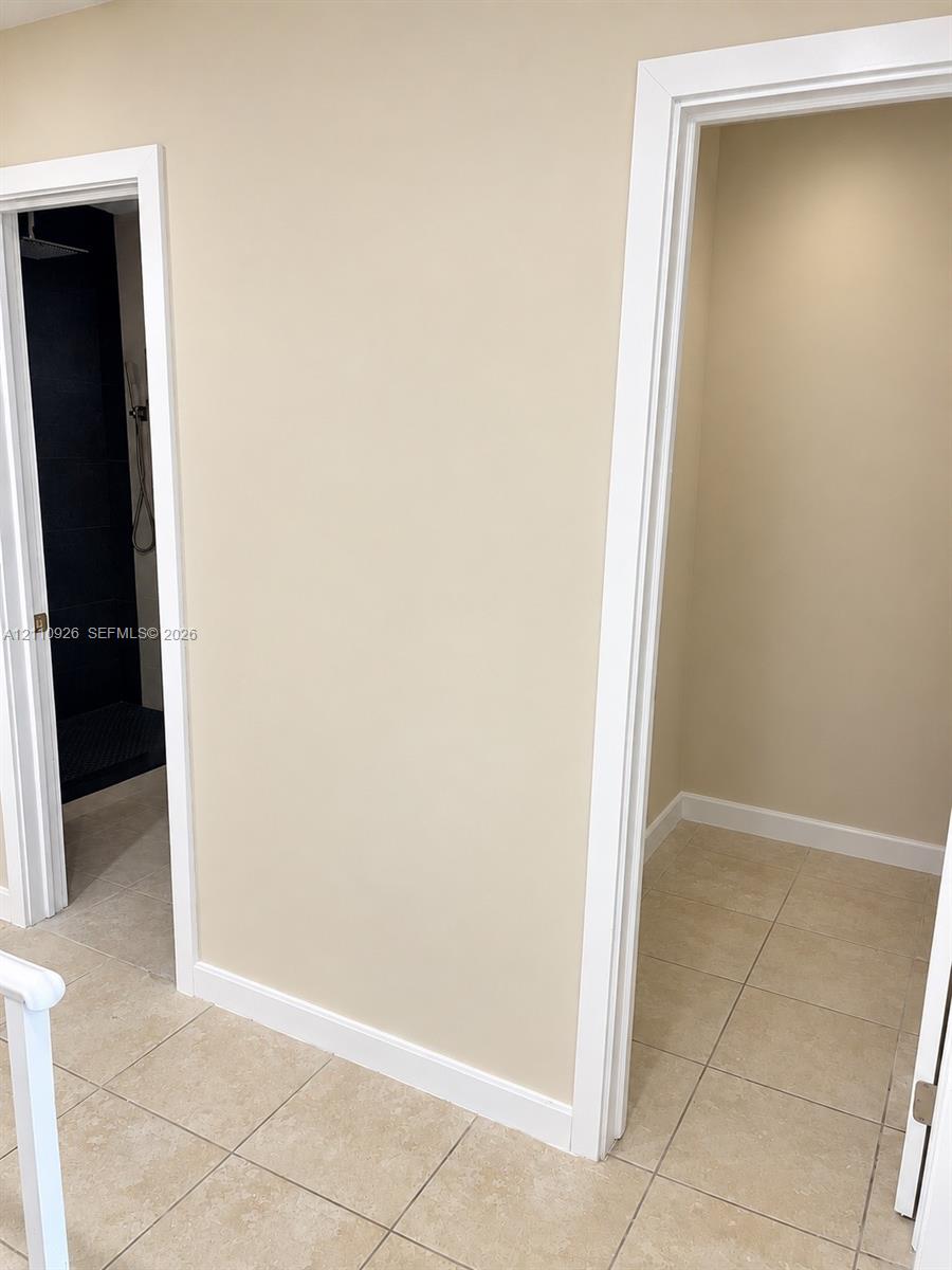 Tiled flooring, high-contrast dark interior shower wall, and minimalist casing trim