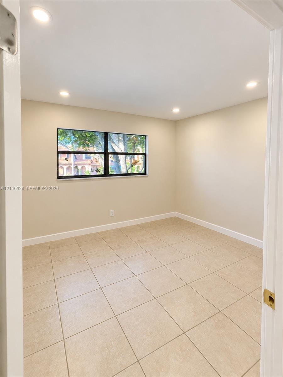 Interior room featuring large-format ceramic tile flooring, neutral wall paint, recessed lighting, and a single-hung window with a dark frame