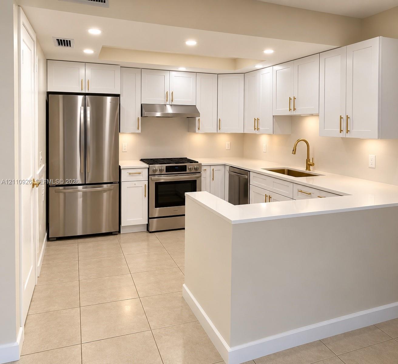 Kitchen featuring white shaker-style cabinetry, quartz countertops, stainless steel appliances, brass-toned hardware, and tile flooring