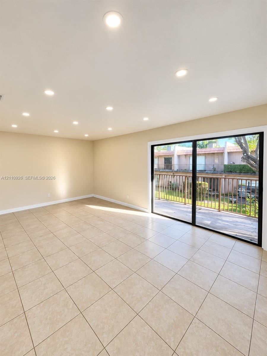 Interior space featuring neutral tile flooring, recessed lighting, and large sliding glass doors opening to a balcony