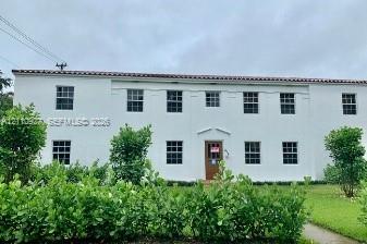 Two-story stucco exterior featuring a terra cotta tile roof, symmetrical window placement, and a centered entryway