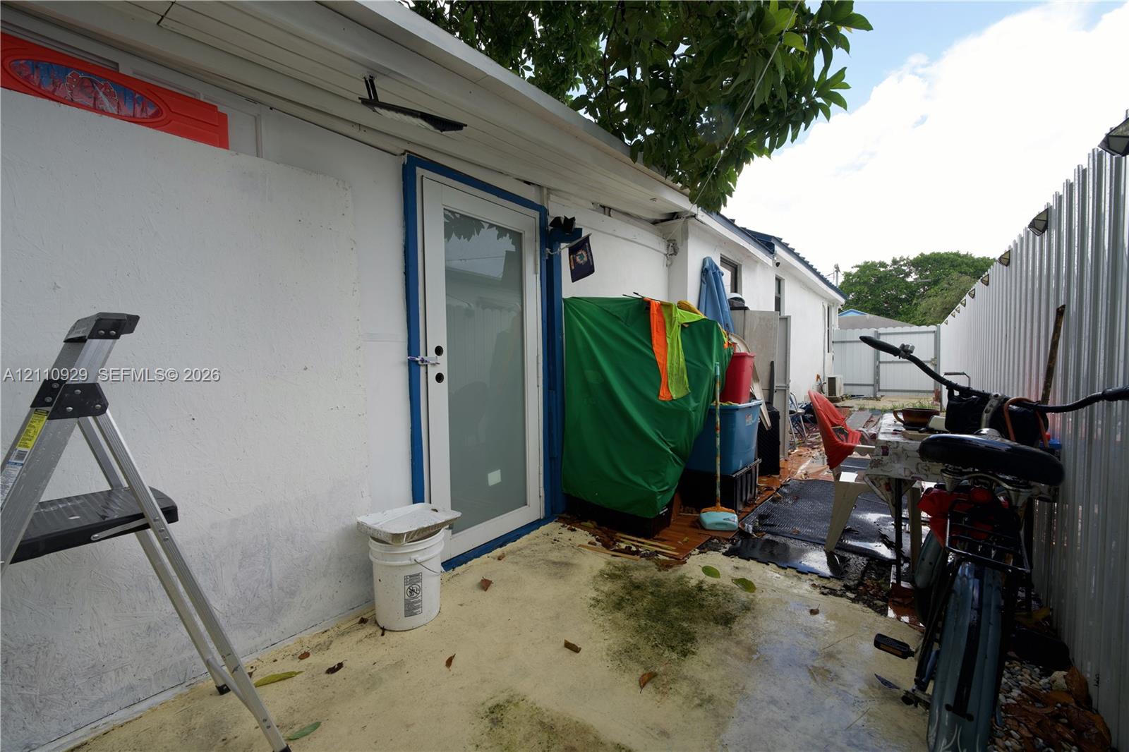 Exterior space featuring a concrete patio, a glass-panel entry door, and a perimeter metal fence
