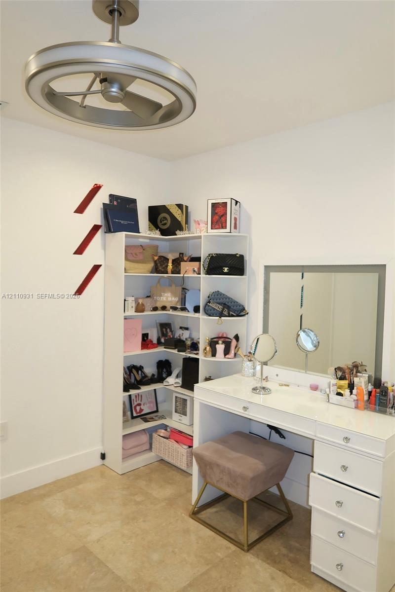 Modern brushed-nickel ceiling fan with integrated LED circular lighting, polished stone flooring, and recessed corner shelving