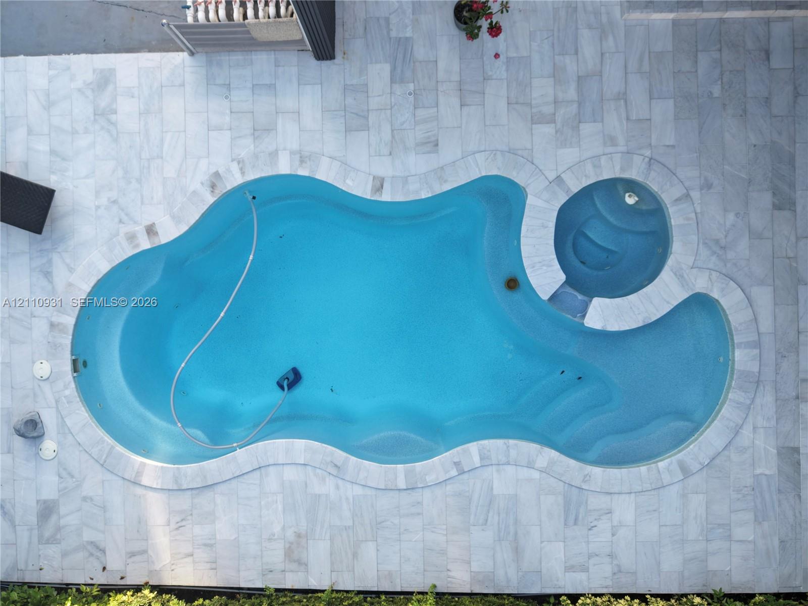 Freeform swimming pool with integrated spa, surrounded by natural stone paver decking