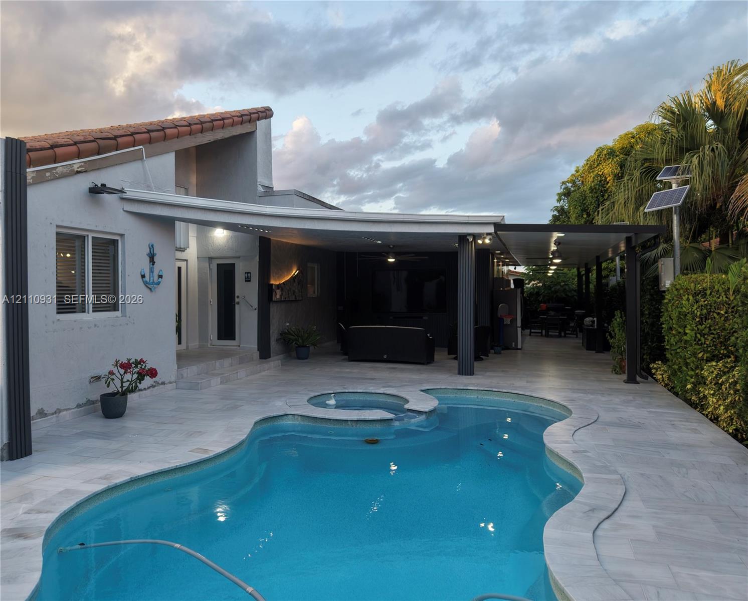 In-ground swimming pool with integrated spa, covered patio area, recessed ceiling lighting, and exterior solar panels