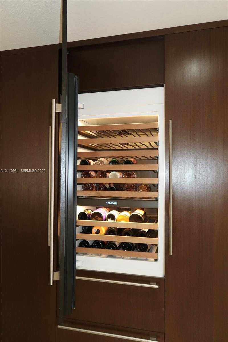 Built-in wine refrigerator featuring wood shelving, integrated cabinetry, and vertical stainless steel hardware