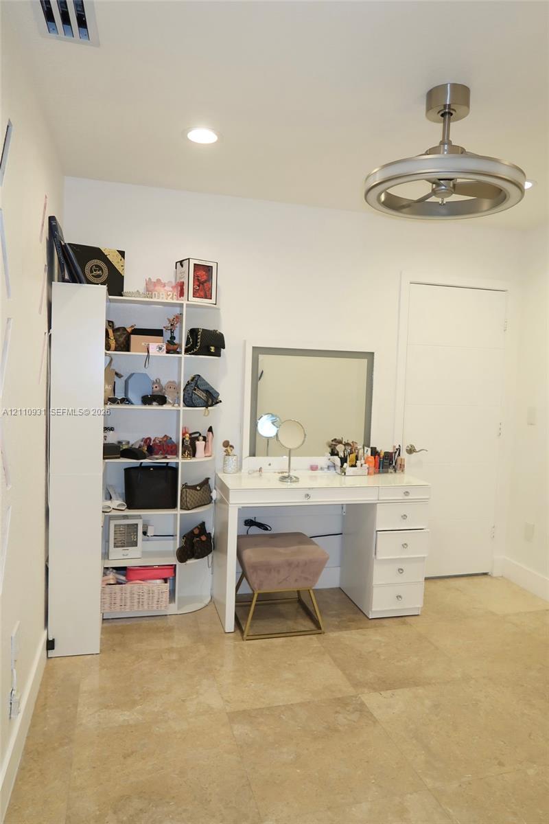 Large-format stone tile flooring, recessed ceiling lighting, and a modern brushed-metal ceiling fan with an integrated circular light fixture