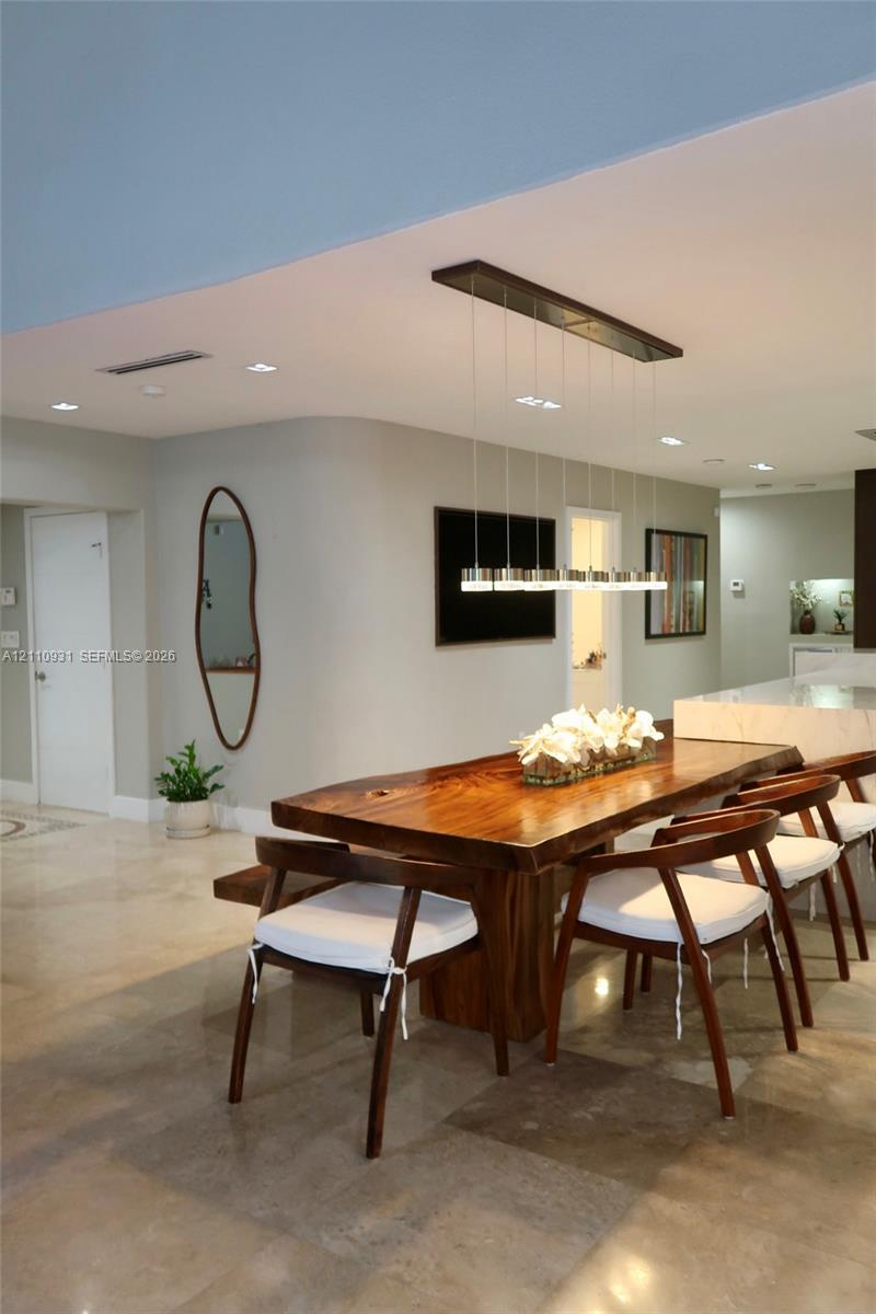 Curved architectural wall detail, polished stone flooring, and contemporary linear multi-pendant lighting fixture