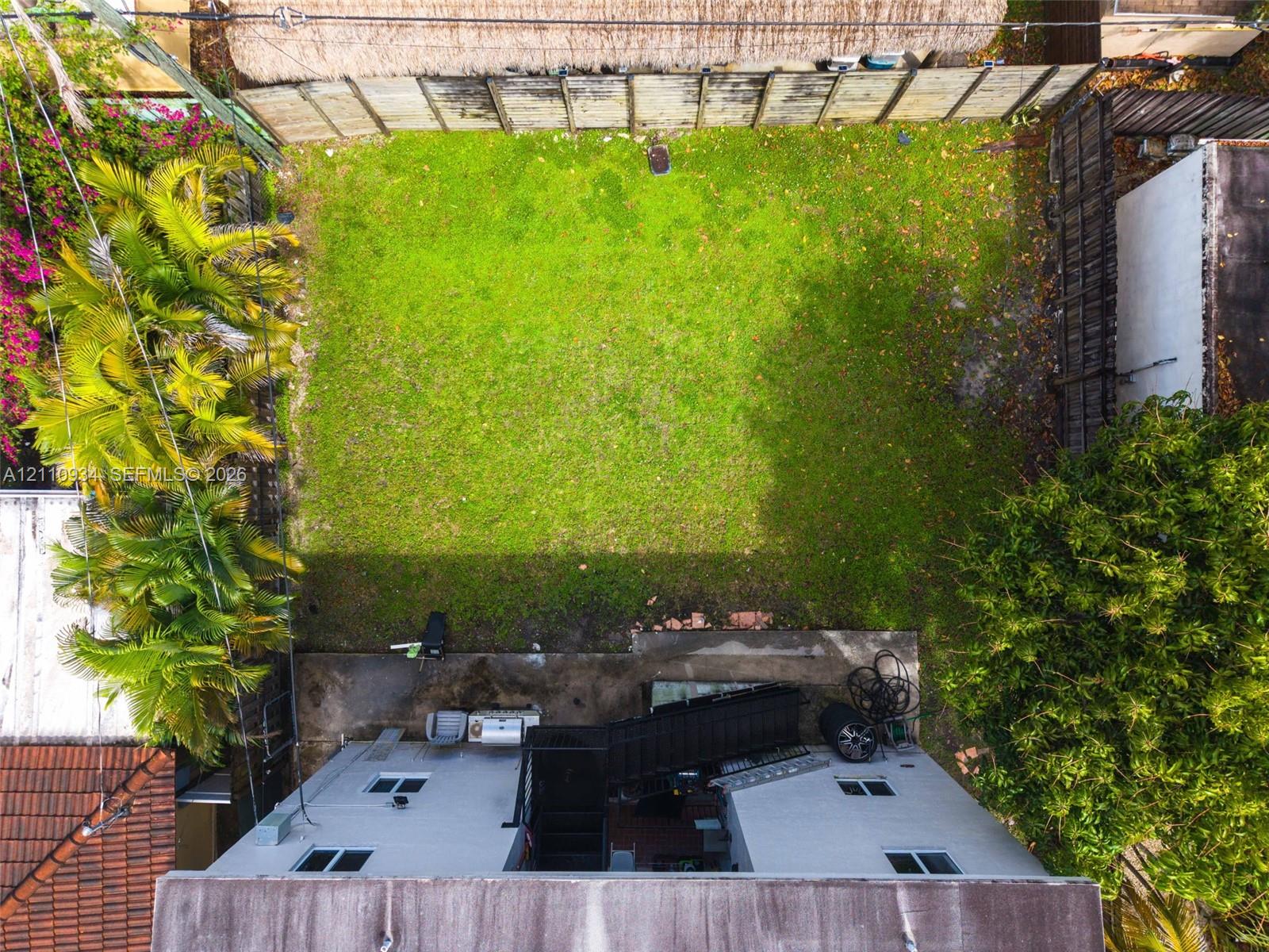 Backyard featuring a grass lawn, perimeter wood fencing, concrete patio, and mature landscaping