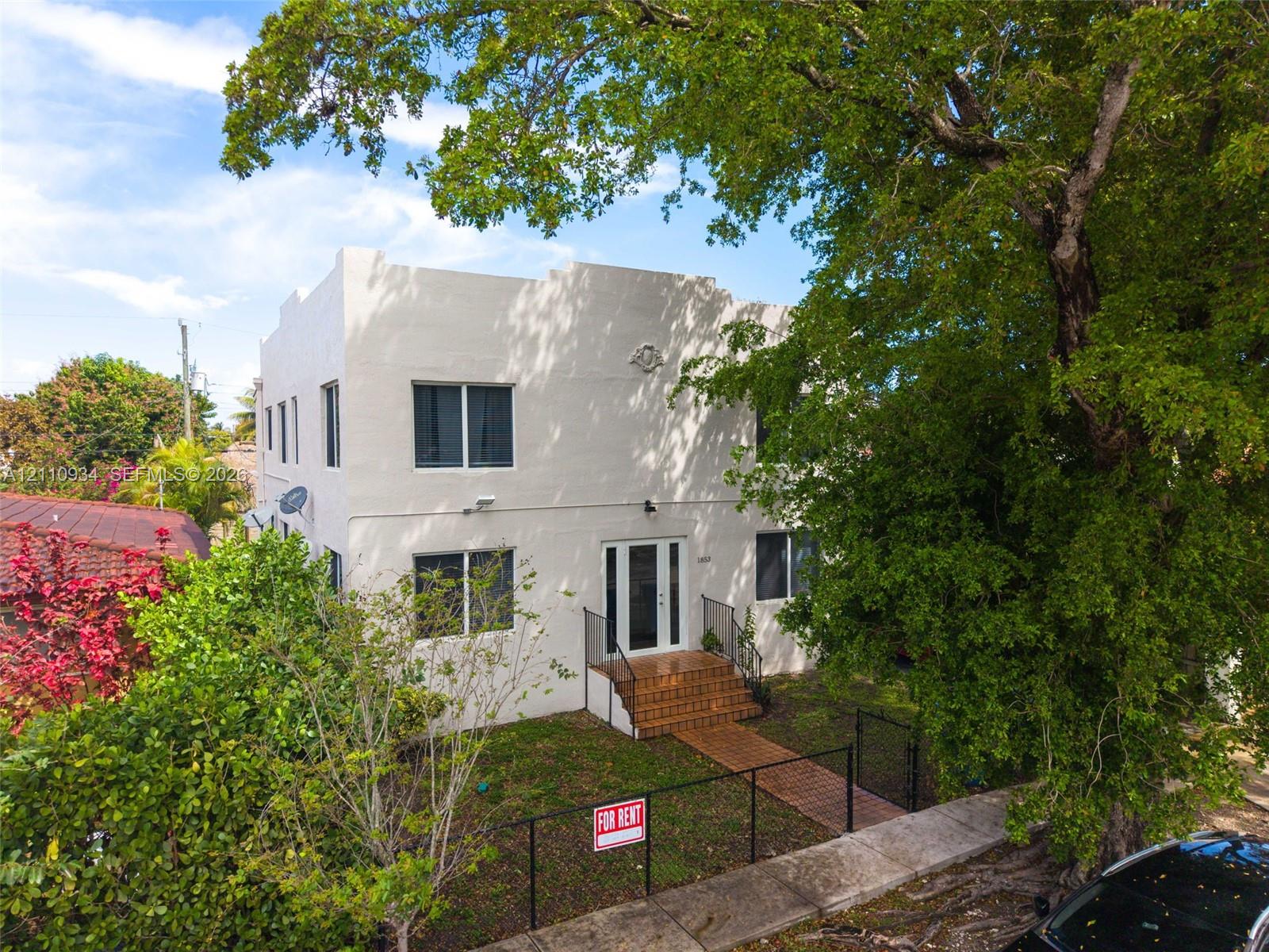 Two-story stucco exterior featuring a flat roofline, ornamental masonry detailing, front brick staircase, and a brick walkway